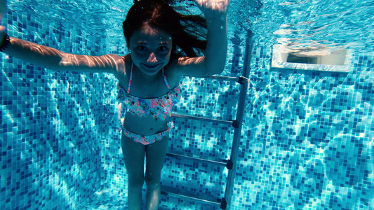 可爱的小女孩在游泳池水下做傻脸视频