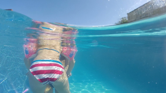 有臂带的可爱小女孩学习游泳池游泳与她的母亲半水下风景视频