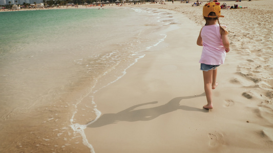 一个可爱的女孩在海滩上奔跑视频