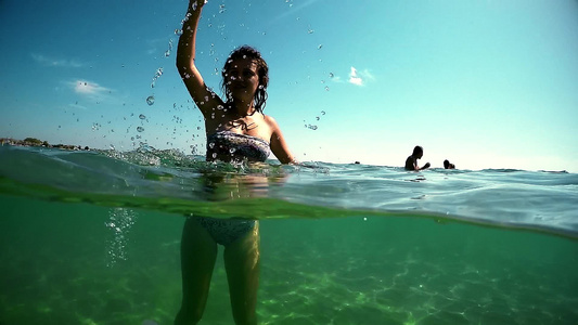 快乐的笑笑女孩带着上浮面罩站在海水中挥舞着Gopro视频