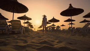 美女在日落时有很多遮阳伞的沙滩上10秒视频