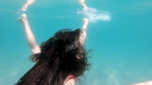 长发女孩在水下游泳头发在海中挥舞慢动作视频