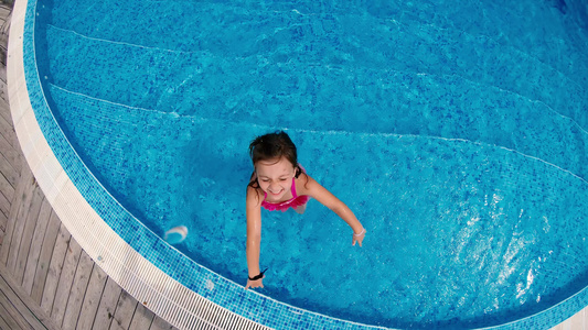 小女孩在游泳池里玩得开心站在泳池里冲着摄影机慢慢的视频