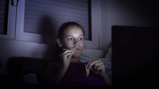 女孩在黑暗中看电视吃零食视频