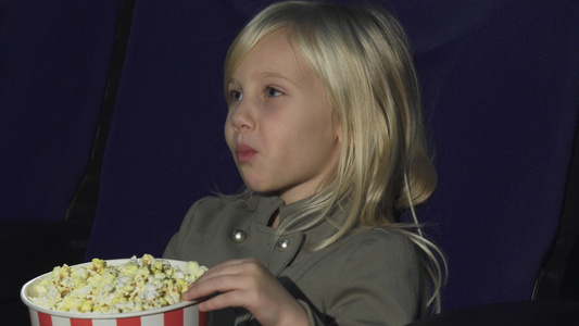 一个可爱的小女孩在电影院吃爆米花视频