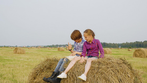 女孩和男孩坐在收割场的干草堆上12秒视频