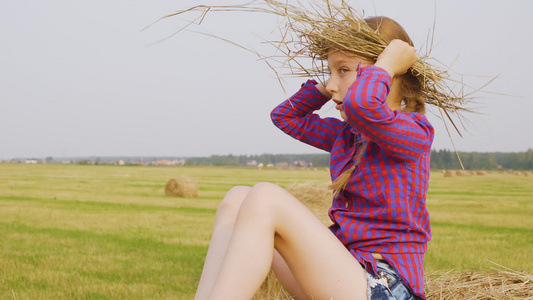 少女坐着干草堆边看视频
