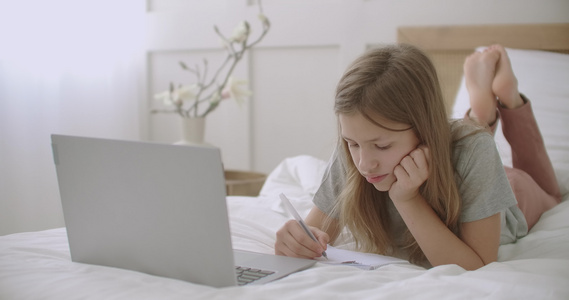 小女孩正在书本中画画和写作躺在房间里笔记本电脑前的视频