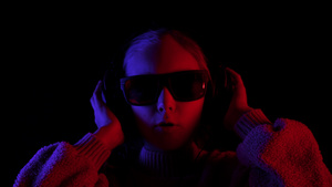 女孩戴着耳机和太阳镜在黑暗中唱歌18秒视频