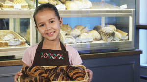 穿着围裙的可爱小女孩在面包店工作拿着一篮子和糕饼8秒视频
