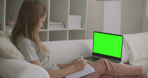 女学生正在用绿色屏幕的笔记本电脑上观看9秒视频