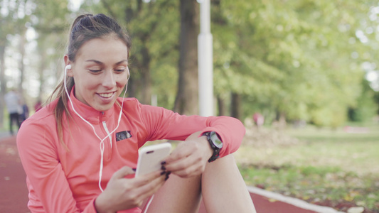 健康女孩坐在公园的天气合成轨道表面时伸展腿部为跑步视频