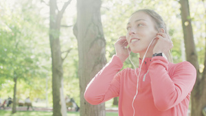 穿着粉红运动服的健身女孩在公园跑时用耳机听音乐7秒视频