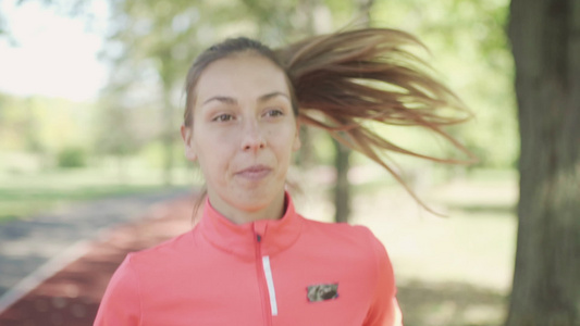 健身跑步女孩在公园跑道上跑步视频
