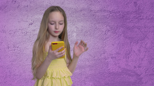 金发长发的金发少女正在紫色墙壁背景上浏览智能手机32秒视频