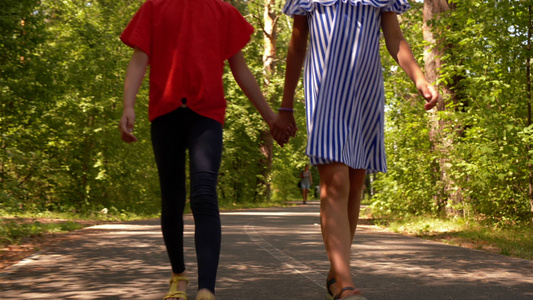 两个十几岁的女孩朋友在公园里走在一起手牵脚合起来视频