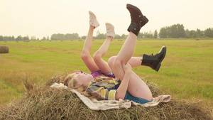 女孩少年躺在干草堆上摇摆着双腿快乐的少女在秋天的干草堆9秒视频