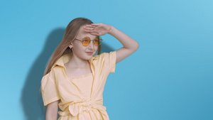 少女少年在工作室的蓝色背景上望着远方戴着黄色眼镜19秒视频