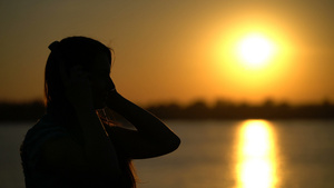 在日落背景用耳机收听音乐的女人14秒视频