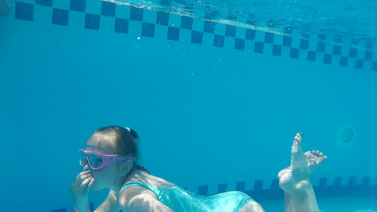 穿着泳装在蓝泳池水下游泳的可爱少女视频