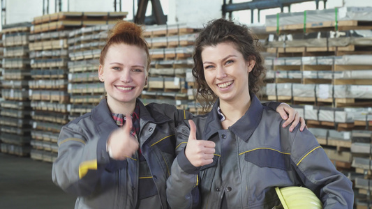 两个快乐的女工厂工人喜欢在仓库露出拇指......视频