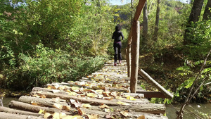 美丽的年轻女子在木桥上的森林公园里跑来跑去7秒视频