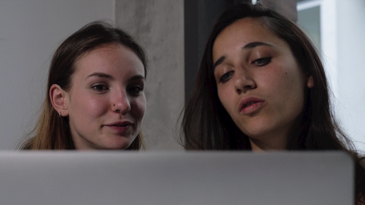 在笔记本电脑屏幕背面的两名年轻妇女的脸部视频