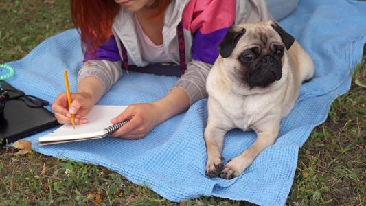 女孩躺在草坪和写作上她的狗趴在旁边视频