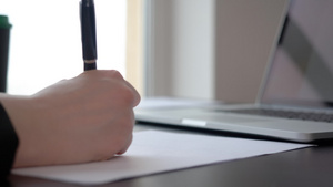 女性手写文档笔放在膝上型电脑背景调查的工作桌上8秒视频