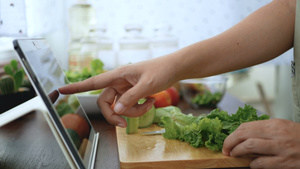 4K女性手切绿色蔬菜准备烹饪原料通过平板电脑在网站14秒视频