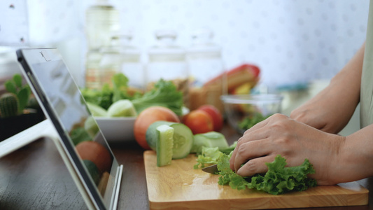 4K女性手切绿色蔬菜准备烹饪原料通过平板电脑在网站视频
