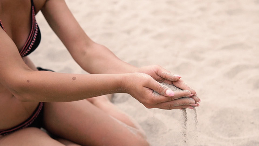 性感女性从沙滩上的手手指上撒沙子慢动作视频