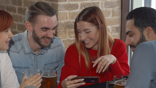年轻人在酒吧一起喝啤酒时使用智能手机同时喝酒视频