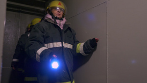 身着防护服和头盔的女性救援人员手持手电筒进入隧道同时26秒视频