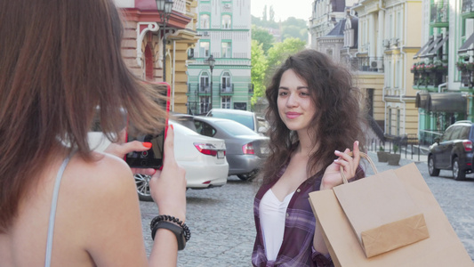 开心的年轻女人拿着购物袋装着照片给朋友看视频