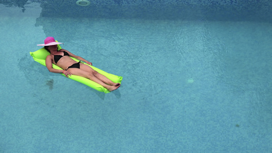 玩得开心的沙滩女孩漂浮在游泳池水里在海洋度假胜地的视频