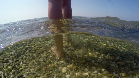 穿着比基尼的性感时装模特在浅海水中走向海边沙石上的视频