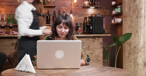 美丽的女孩在她的电脑上打字同时在咖啡店喝咖啡16秒视频