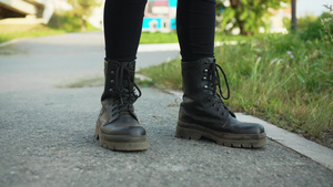 穿着黑色皮靴的女性腿在夏天站在柏油路上穿着皮鞋的女孩17秒视频