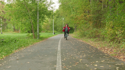 小男孩骑自行车的人在绿色夏日公园的小路上骑自行车在视频