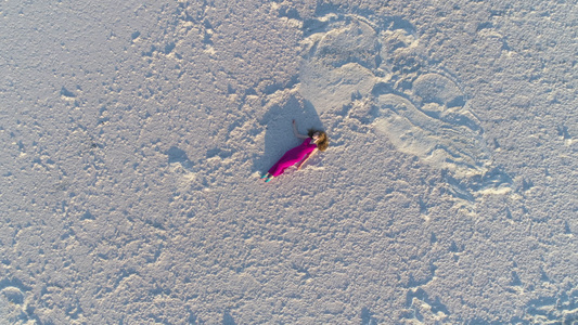 身着红裙子长发的幼女躺在盐湖白面上无人驾驶飞机在旋转视频