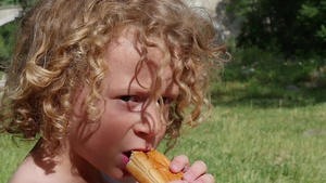 一个金发小男孩吃蛋糕户外慢动作35秒视频