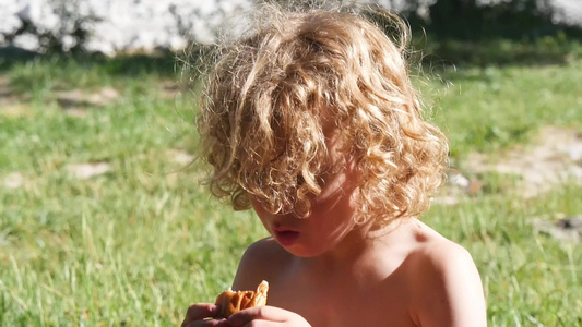 一个金发小男孩吃蛋糕户外视频