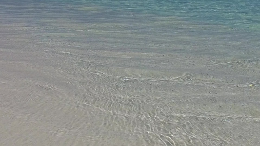 阳光明媚的宁静海岸沙滩旅游沿浅海和接近冲浪的白沙背景视频