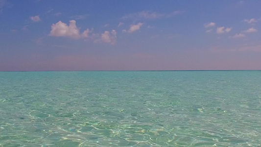 通过透明的海洋和靠近海浪的白色沙滩背景关闭了天堂环礁视频