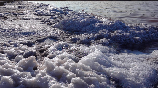 白泡沫和桌盐水晶体覆盖盐湖岸上的石块包括盐湖边的石块视频