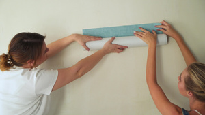 建筑工地的两名女孩在墙上粘胶墙纸10秒视频