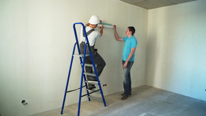 建筑工地的两名工人将墙纸粘到墙上14秒视频
