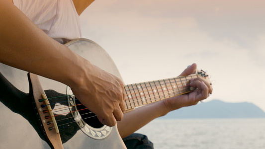 日落时在沙滩上弹声吉他的人的近身感觉放松视频