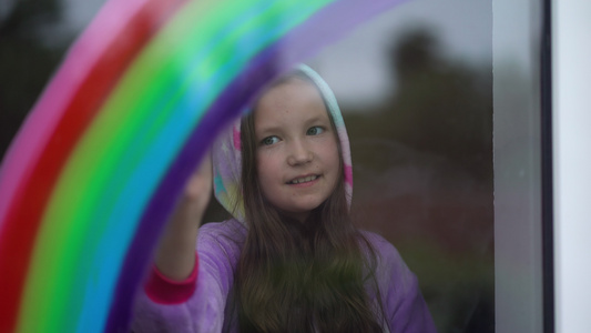 穿着睡衣的女孩在家里的窗户上画彩虹她很爱吃晚饭视频